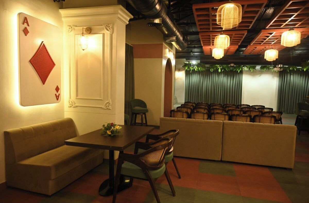 A cozy lounge area with a sofa, a table, and chairs, a decorative wall with a playing card, and a seating area with multiple chairs.
