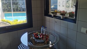 Une salle de bain avec une table ronde en verre, une bouteille d’eau et un plateau contenant des fraises et des fleurs.