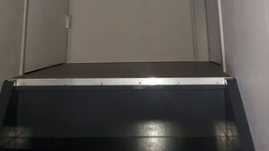 Un pasillo estrecho con una puerta a la izquierda y una escalera que sube a una plataforma.
