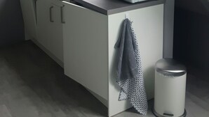 Una cocina compacta con tragaluz, microondas, cafetera y un cubo de basura.
