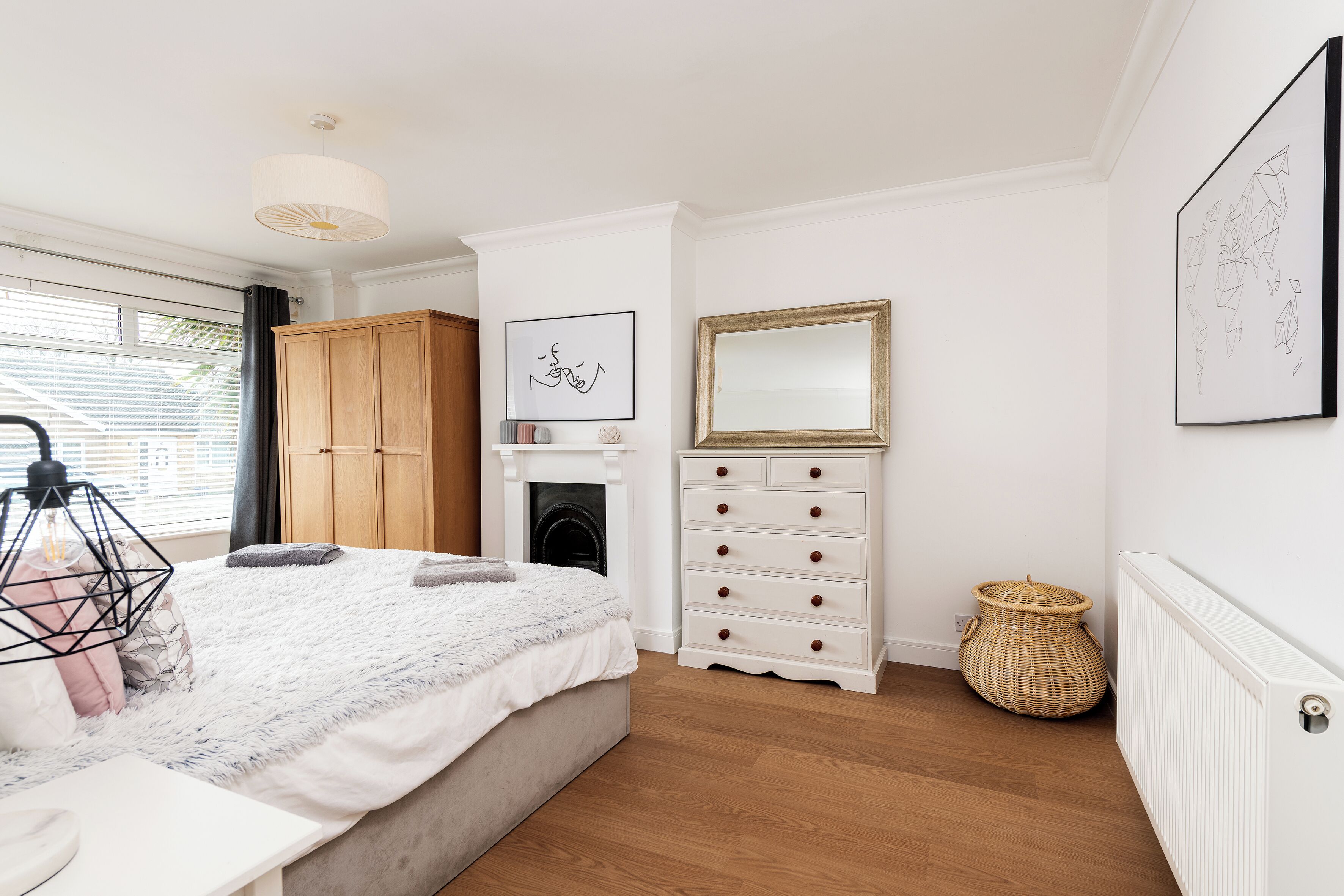 A bedroom with a bed, dresser, and artwork on the wall.