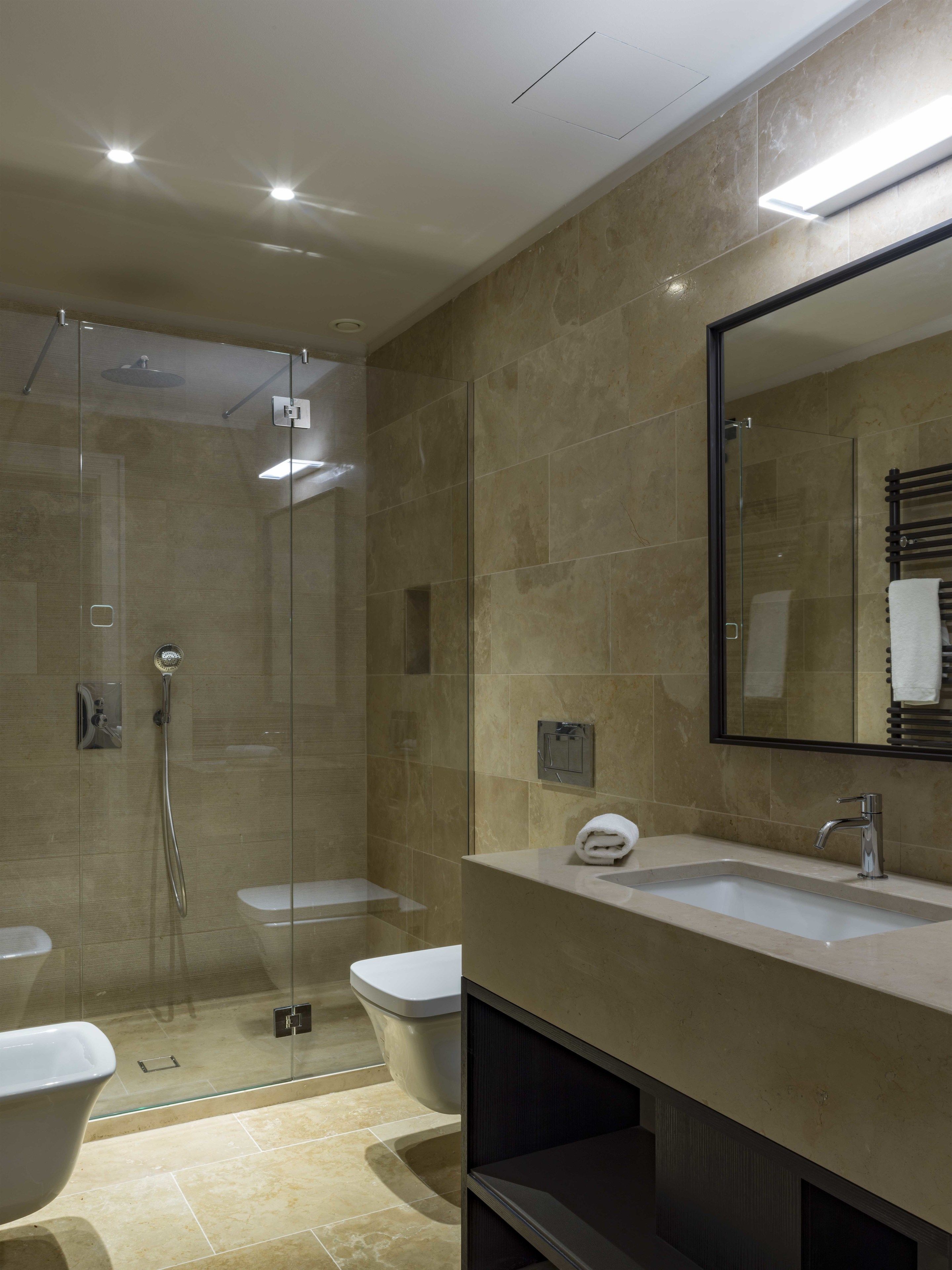 A modern bathroom with a glass-enclosed shower, a freestanding bathtub, and a vanity with a mirror.