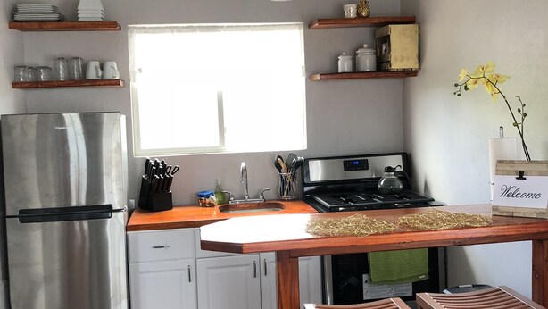 A compact kitchen with white cabinets, a stainless steel refrigerator, and a window providing natural light.