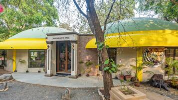 A restaurant with a green and yellow exterior, a brick facade, and a tiger mural.