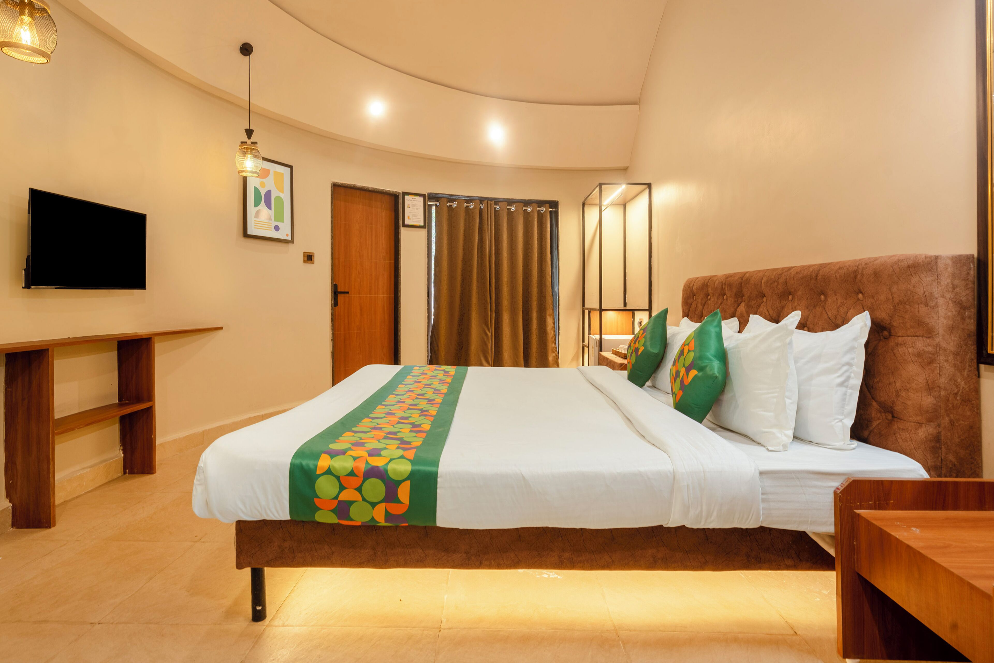 Une chambre d’hôtel avec un grand lit, une télévision, un bureau en bois et un miroir.