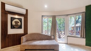 Una habitación moderna con un sofá, un cuadro enmarcado y un gran ventanal con cortinas.