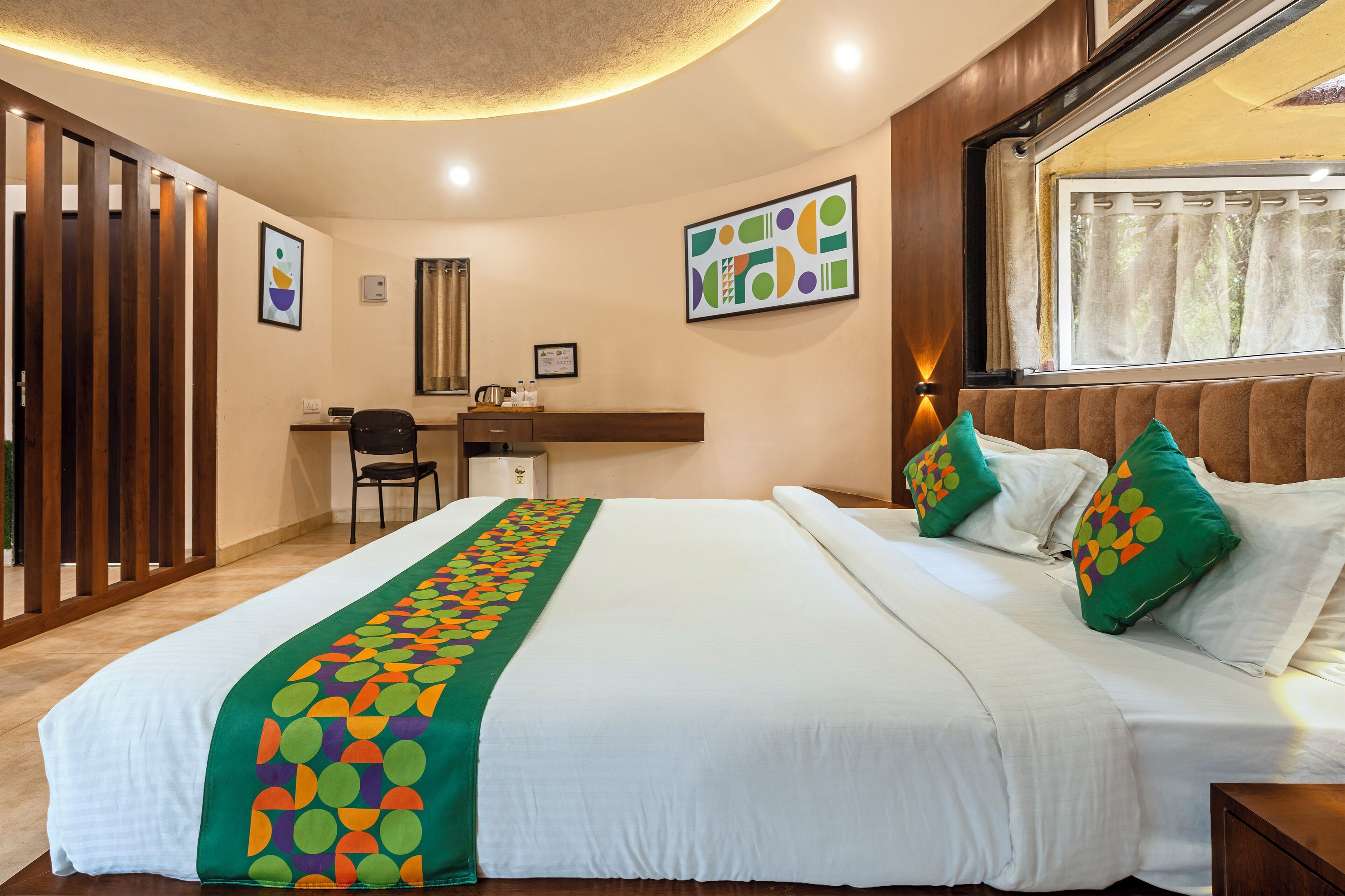 A hotel room with a large bed, a desk, a chair, and a window with curtains.