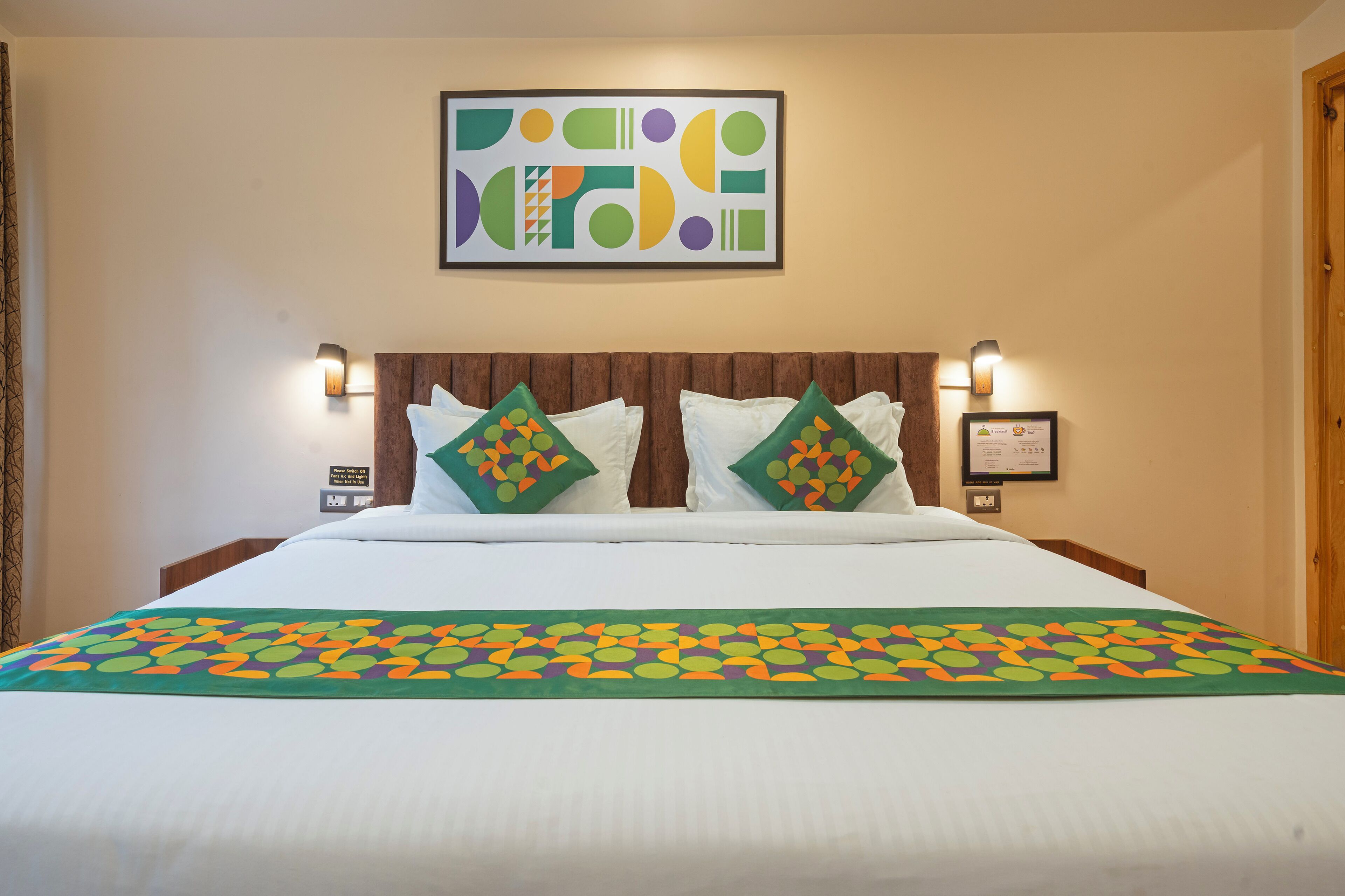Una camera d'albergo con un letto, due cuscini, un quadro incorniciato e un lampadario a parete.