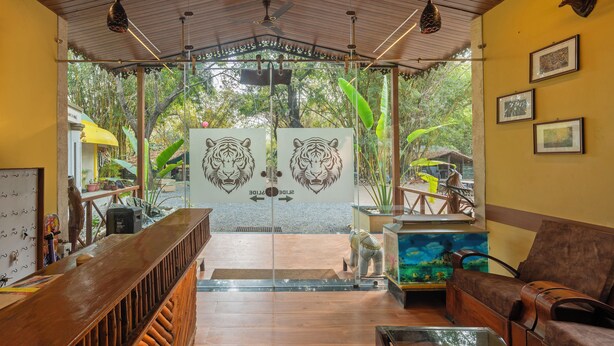 Un área de recepción con un mostrador de madera, un sofá y una puerta de cristal con motivos de tigre.