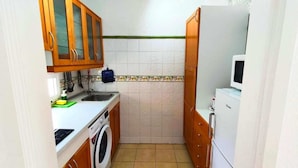 A compact kitchen with a washing machine, a sink, and a microwave.