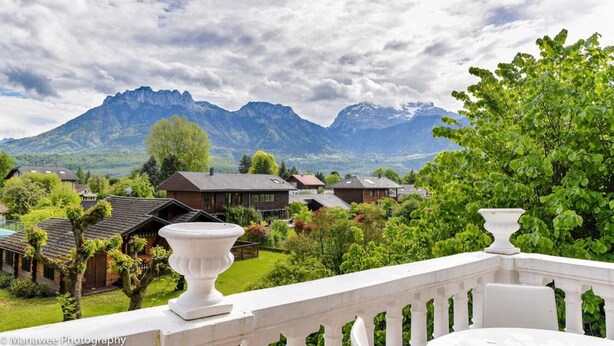 A balcony with white balustrades overlooking a mountainous landscape with houses and greenery. - Villa Ariane Saint-Jorioz (Saint-Jorioz)