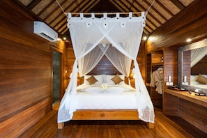 A wooden cabin-style bedroom with a four-poster canopy bed, a wooden bench, and a mirror on the wall. - Royal Cottage Nusa Lembongan (Lembongan Island)