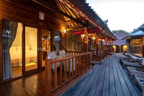 Une terrasse en bois avec des chaises longues et un espace salon abrité.