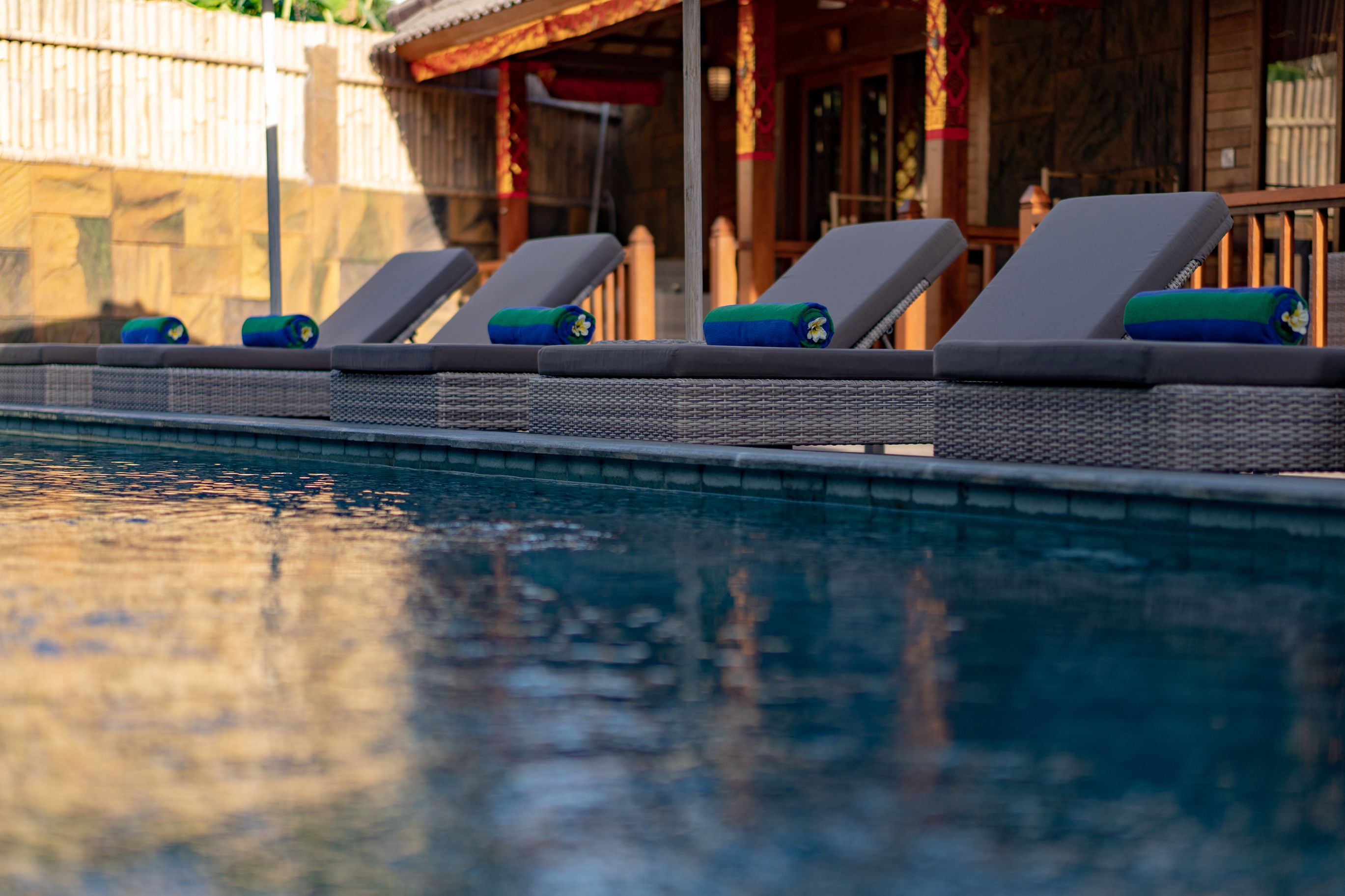 A poolside area with lounge chairs and a stone wall in the background.