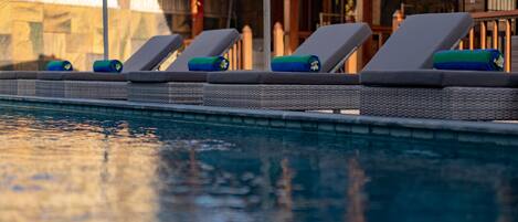 A poolside area with lounge chairs and a stone wall in the background.