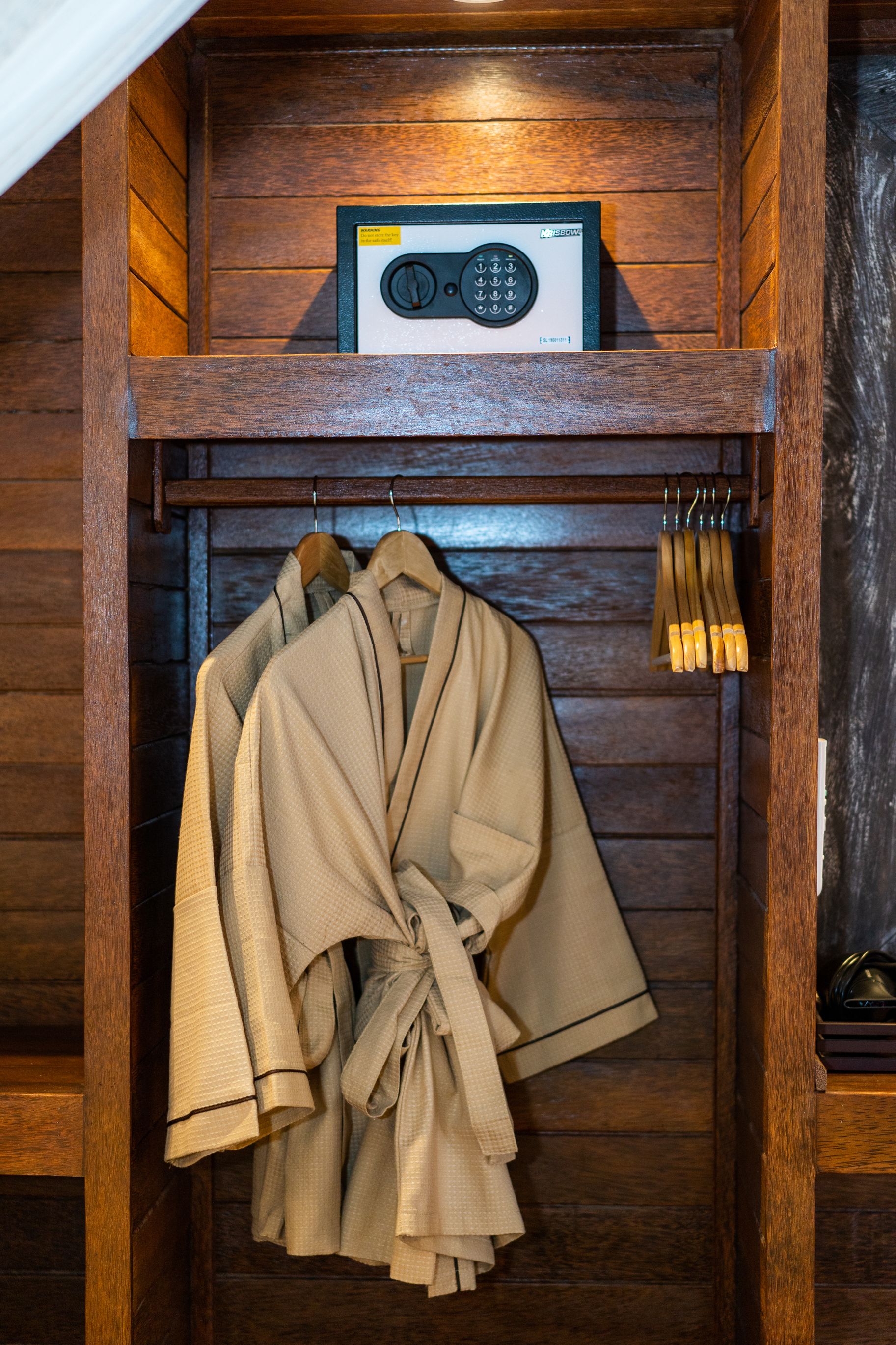 A wooden closet with a radio and several robes hanging on a rack.