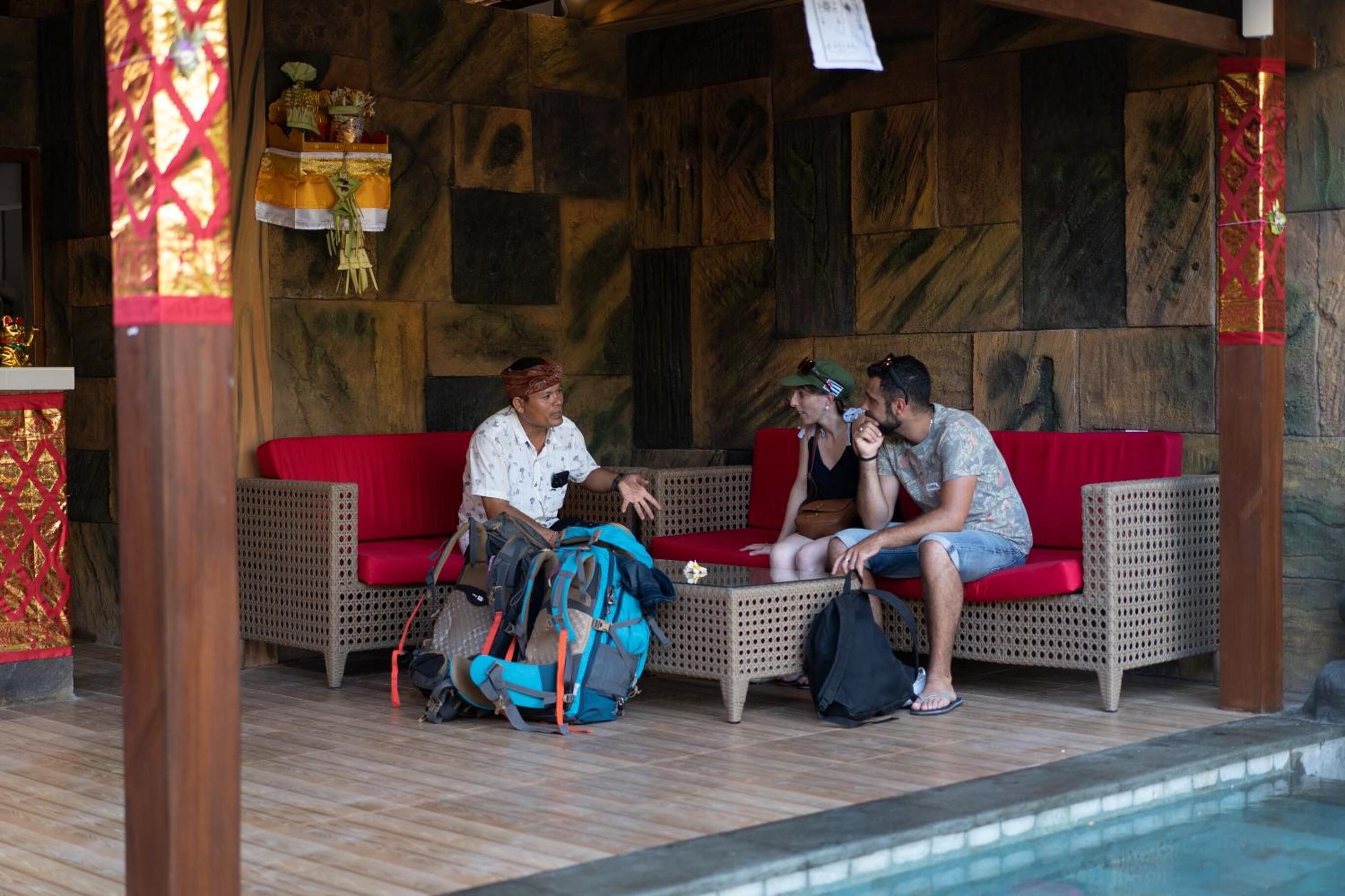 Un espace de détente abrité, avec des meubles en osier, et une piscine en arrière-plan.