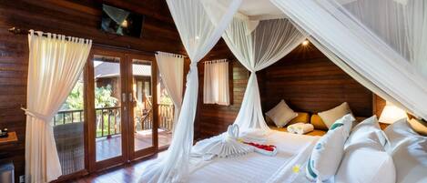 A bedroom with a four-poster bed, white bedding, and a balcony with curtains.