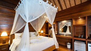 A four-poster canopy bed with white linens, wooden headboard, bedside lamps, and a small bedside table. - Royal Cottage Nusa Lembongan (Lembongan Island)