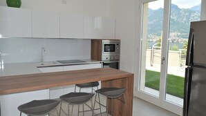 Una cocina moderna con una isla de madera, taburetes de bar, un microondas y un horno.