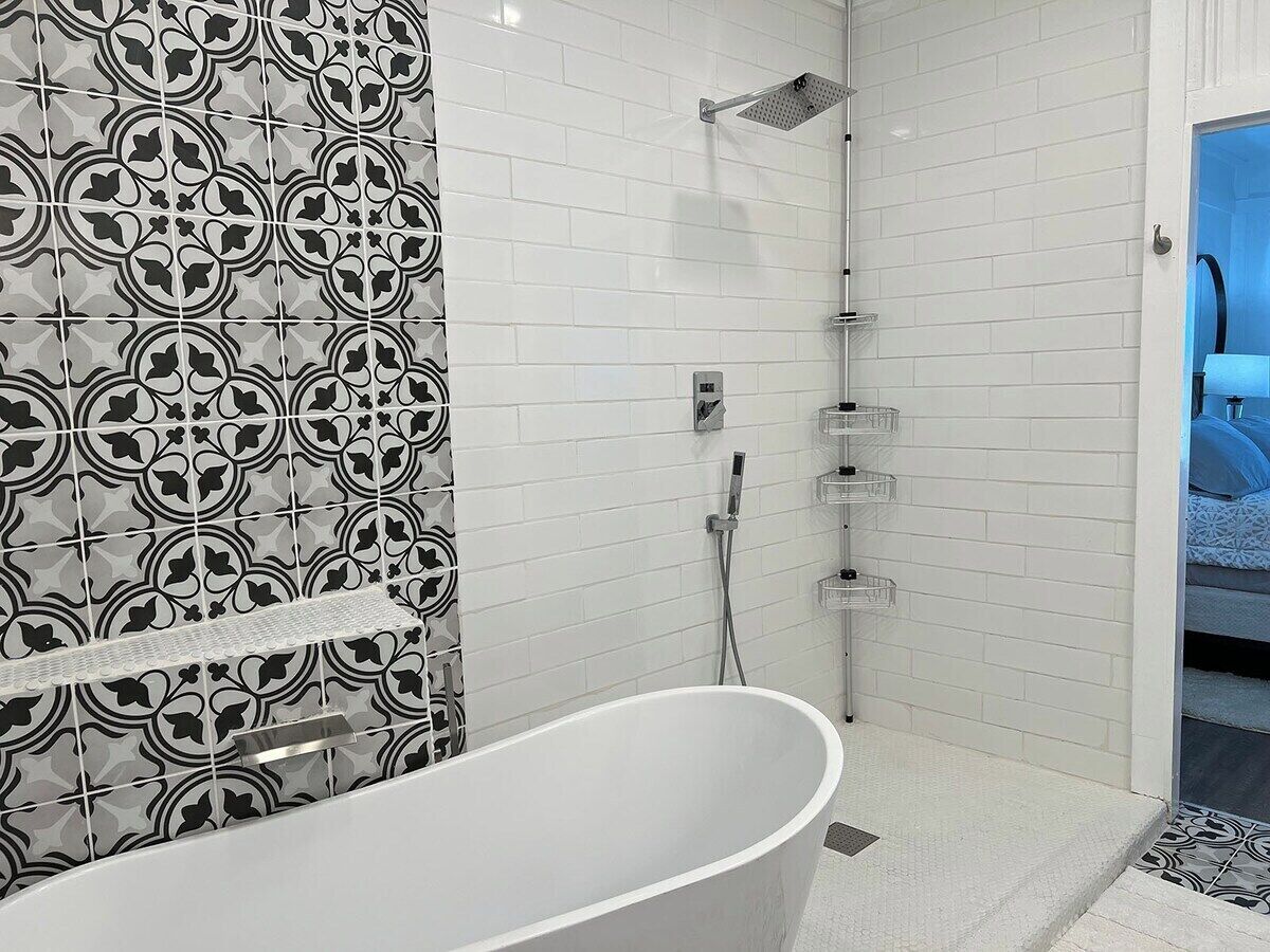 Une salle de bain moderne avec une baignoire sur pieds, une douche équipée d’un pommeau de douche amovible et un mur recouvert de carreaux décoratifs.