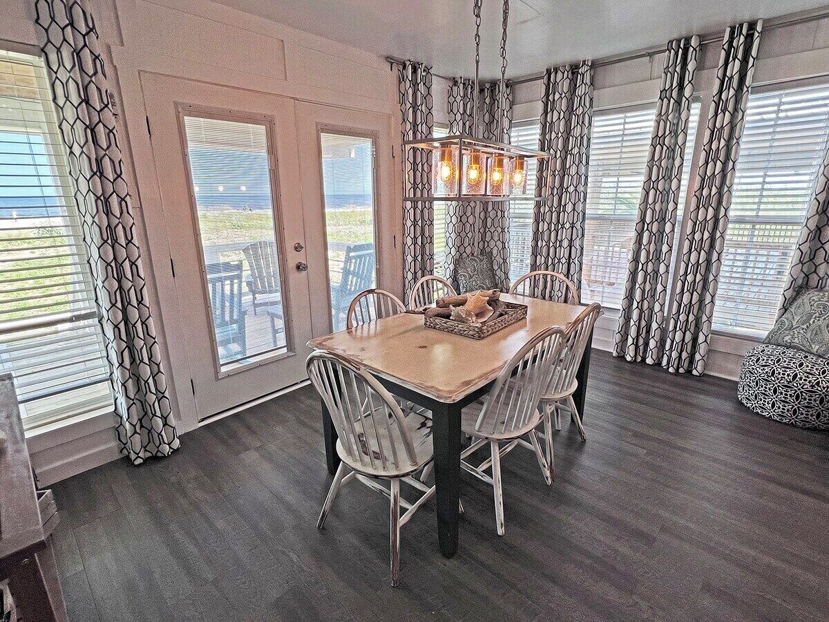 A dining area with a wooden table and chairs, a chandelier, and patterned curtains.