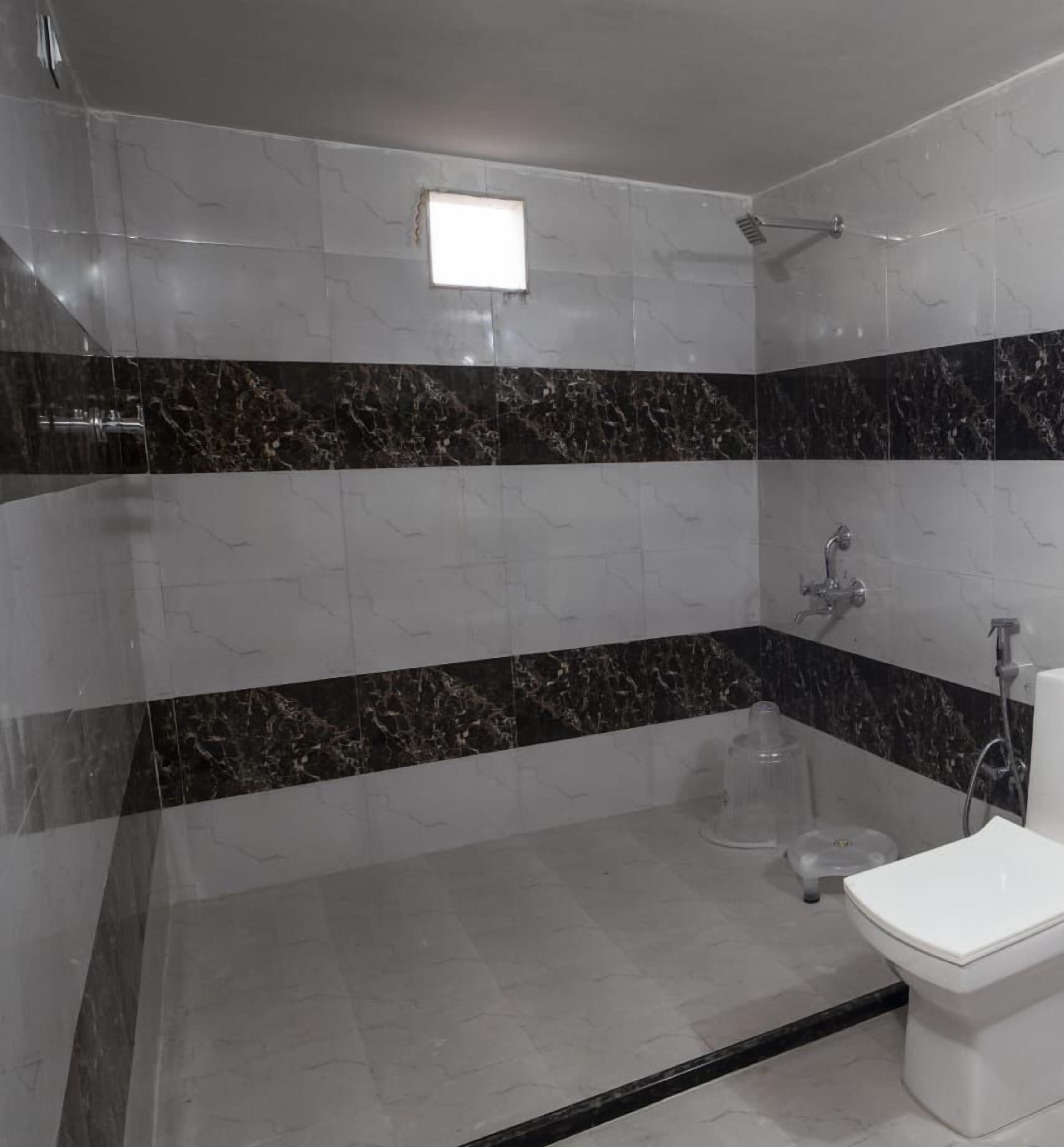 Un baño con baldosas de mármol blanco y negro, una ducha y un inodoro.
