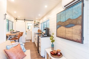 Una cocina compacta con zona de comedor, un sofá con cojines y un cuadro en la pared.