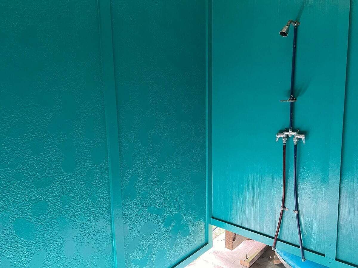Habitación color turquesa con zona de ducha, que incluye un cabezal y una manguera.