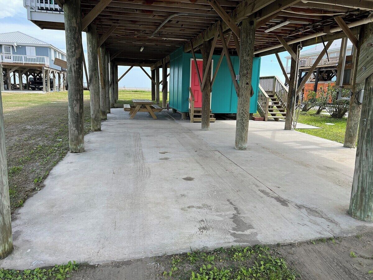 A covered outdoor area with a concrete floor, wooden posts, and a picnic table.