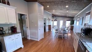 A spacious kitchen with wooden flooring, white cabinetry, and a central island. - Sassy Seagull Beachfront and Sunrise (Grand Isle)