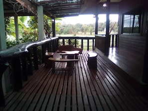 Une terrasse en bois avec une table et des chaises, offrant une vue sur un paysage verdoyant et luxuriant.