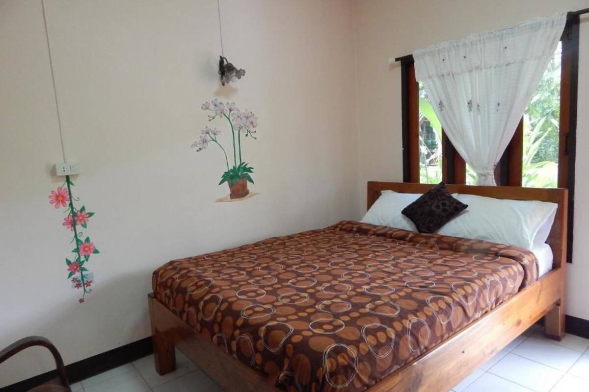 Un dormitorio con una cama de madera, una planta en maceta y un adorno en la pared.
