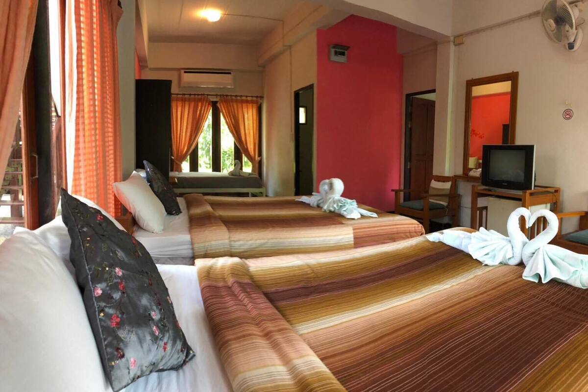 Habitación de hotel con dos camas, televisión y espejo.
