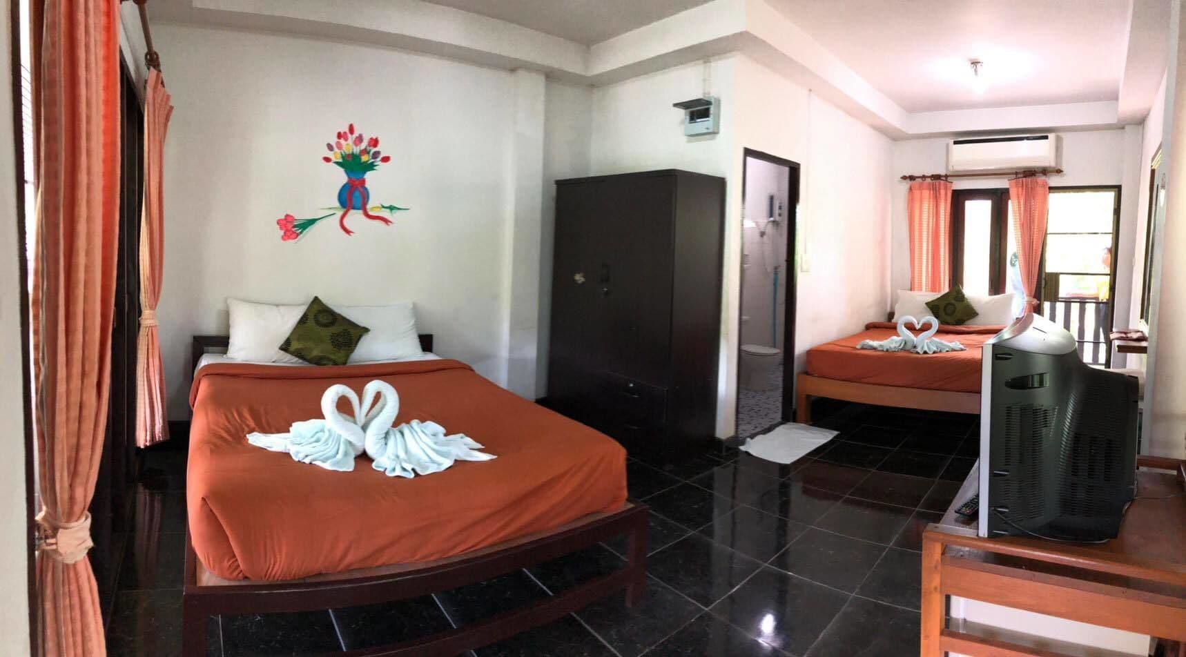 Une chambre d’hôtel avec un lit, une télévision, une armoire et un miroir.