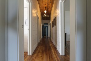 A hallway with wooden floors, white walls, and a wooden ceiling. - Restored 1930s Uptown Bungalow 2 min. to Magnolia (Waco)