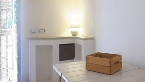 Et minimalistisk rum med en hvid kamin, et træbord og en lampe.