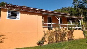 A single-story building with a flat roof, a balcony, and a small garden area. - Sitio Oliveira Ibiúna (Ibiuna)