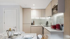 Et moderne køkken med spiseplads, med et hvidt bord dækket med tallerkener, bestik og glas, samt en champagnekøler.