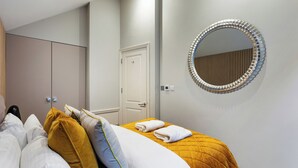 Et hotelværelse med en seng, et rundt spejl, et skab og en dør.