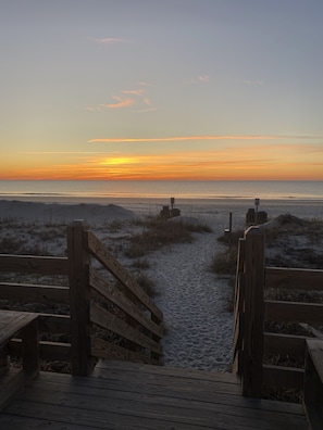 A wooden boardwalk leading to a beach with a sunset in the background. - Steps to the Beach, Pool, Dog friendly! (Surfside Beach)