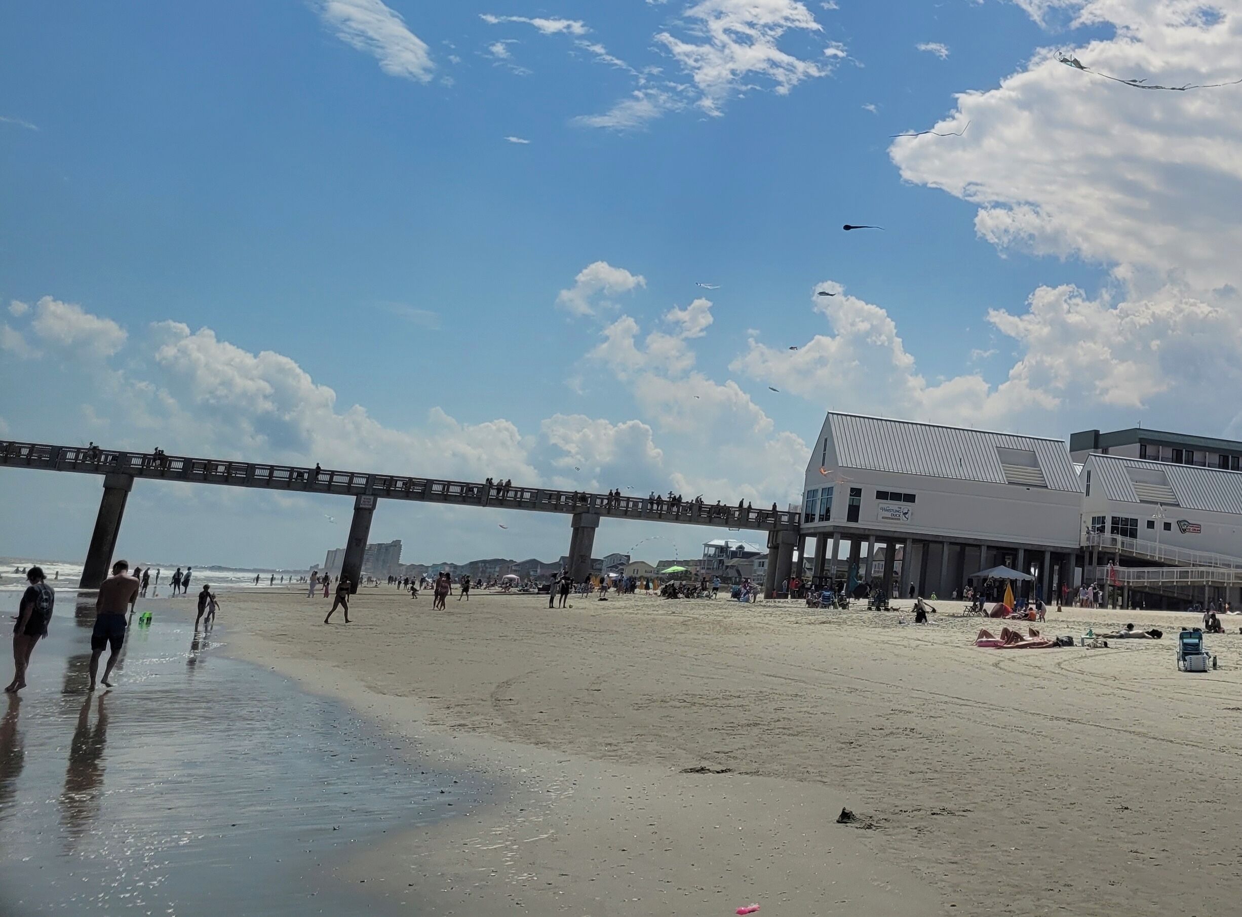 A beach with a pier and a building with a sign.
