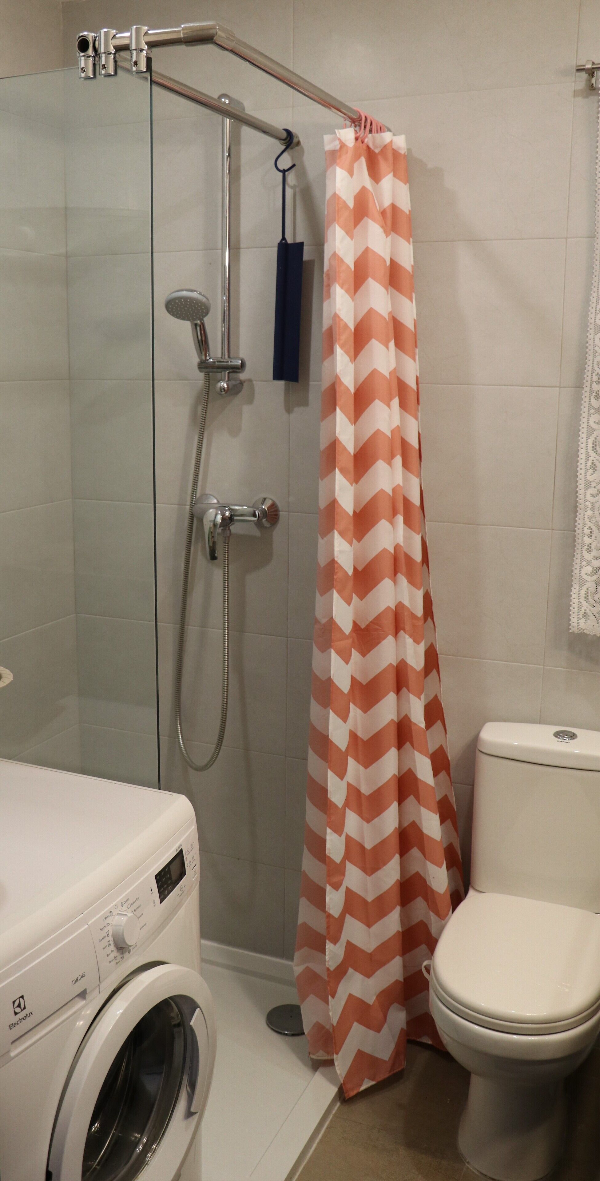 A bathroom with a shower, a toilet, and a washing machine.