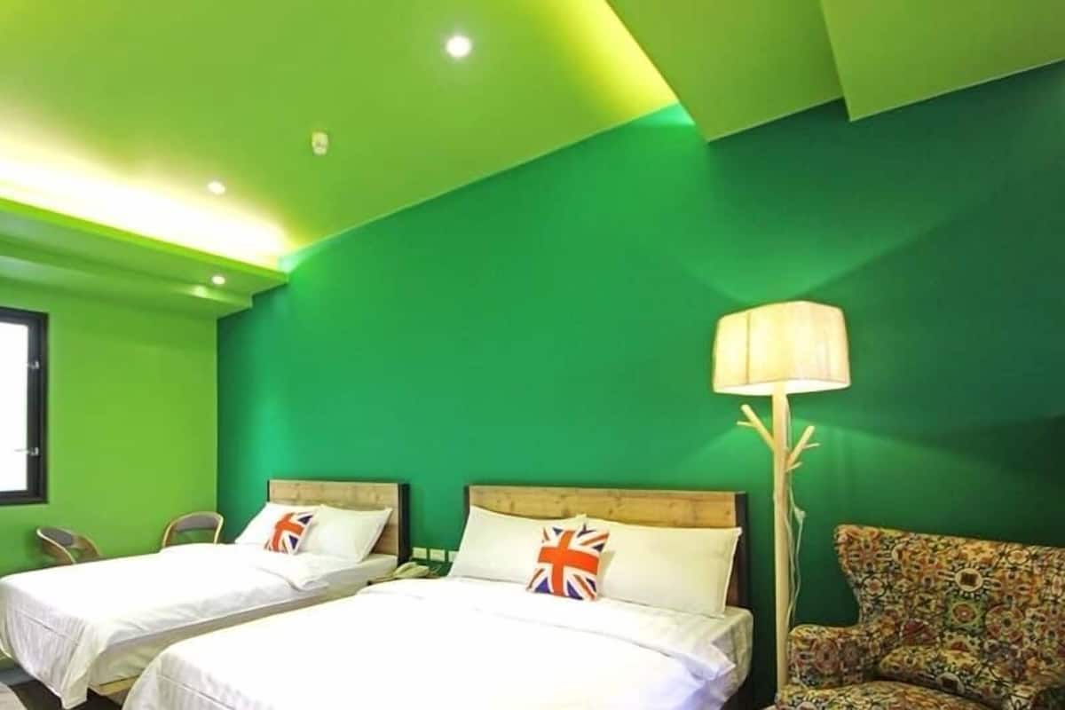 A room with two beds, a door, a chair, and a lamp.