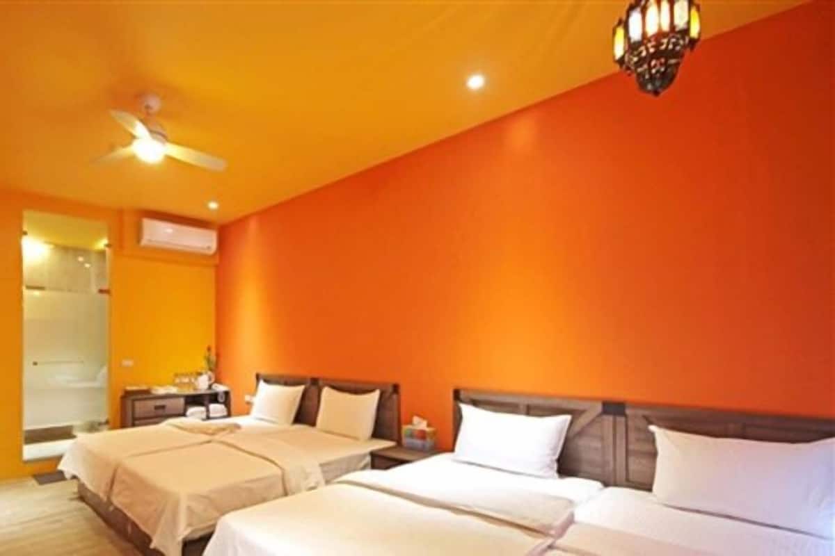 A hotel room with two beds, a ceiling fan, an air conditioning unit, and a nightstand with a lamp.