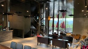 Ein modernes Interieur mit einer Rezeption, einer Sitzecke und einer Treppe, die auf eine Außenterrasse führt.
