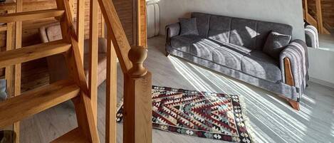 Un interior de madera con una escalera, un sofá y una alfombra estampada.