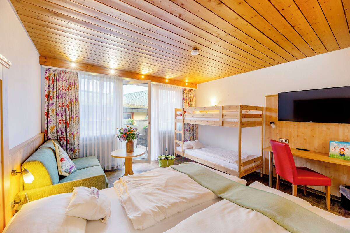 Une pièce confortable avec un lit superposé, un canapé, un bureau avec une chaise et un téléviseur.