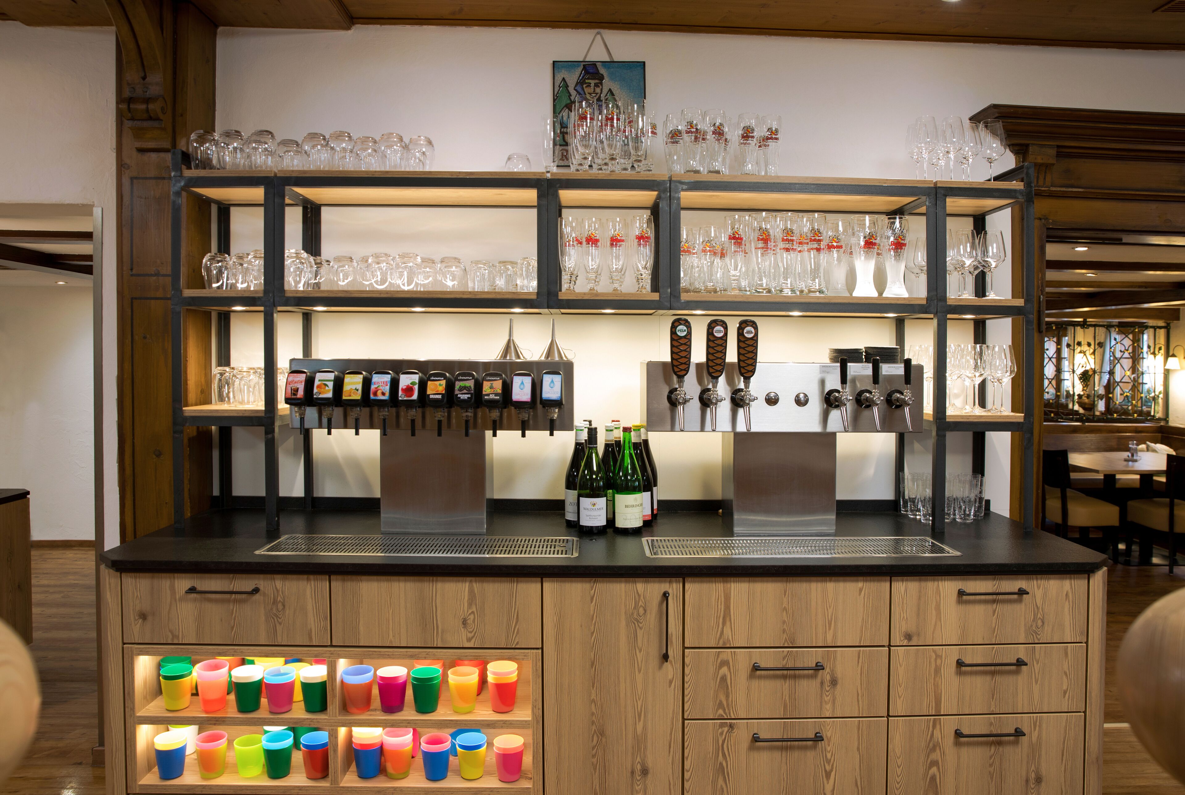 Eine Bar mit Regalen voller Gläser, Flaschen und bunten Bechern.