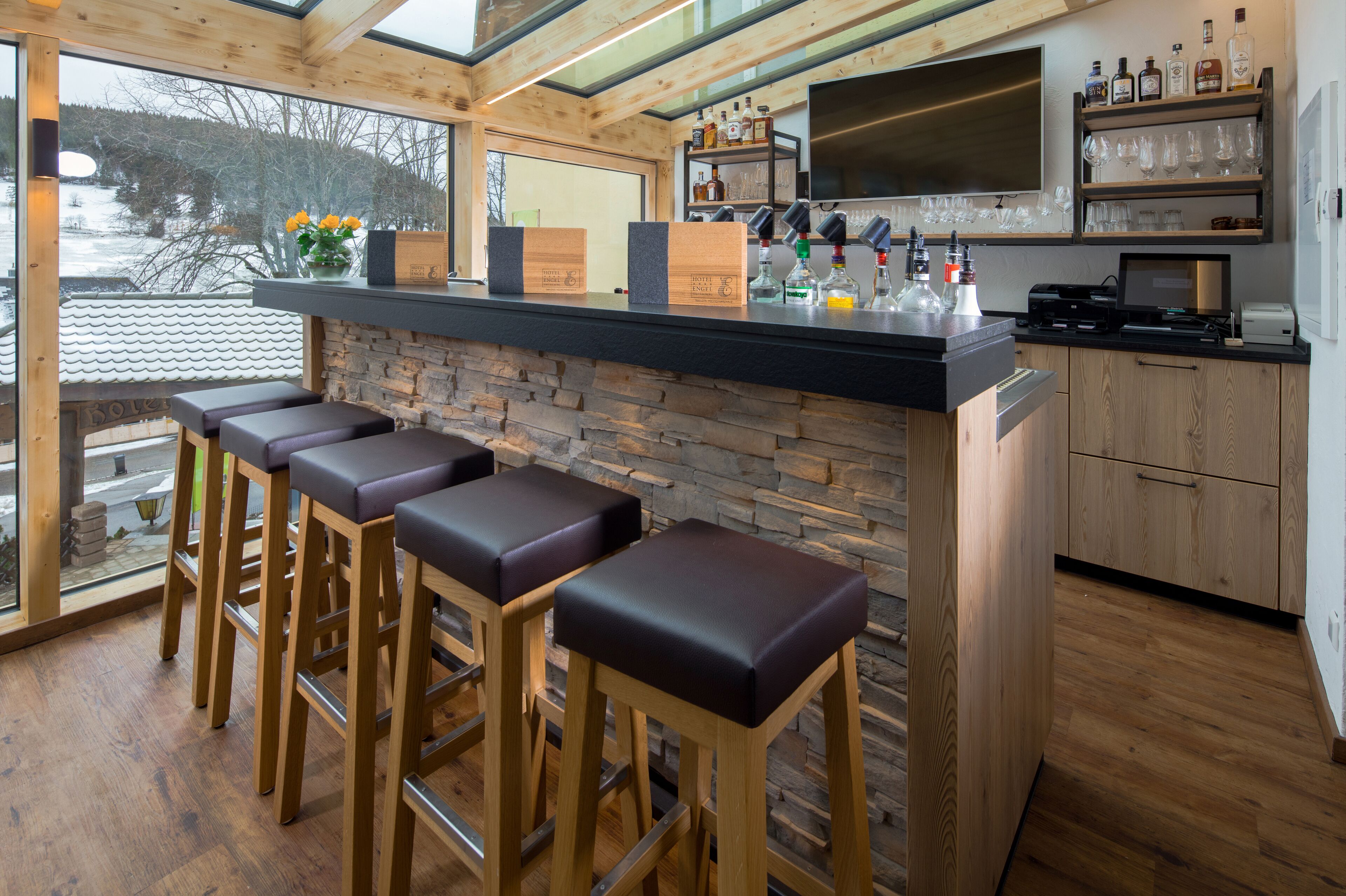 A bar area with wooden stools, a stone counter, and a view of the outdoors.